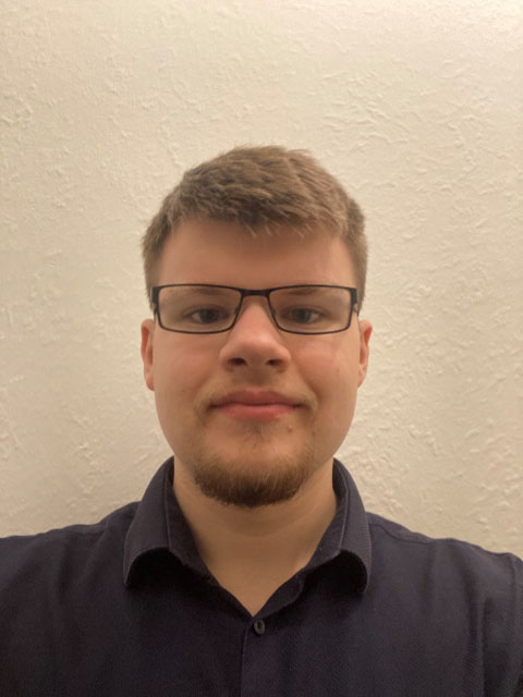 Doctoral Researcher Caspar Worth wearing a dark shirt in front of a light background